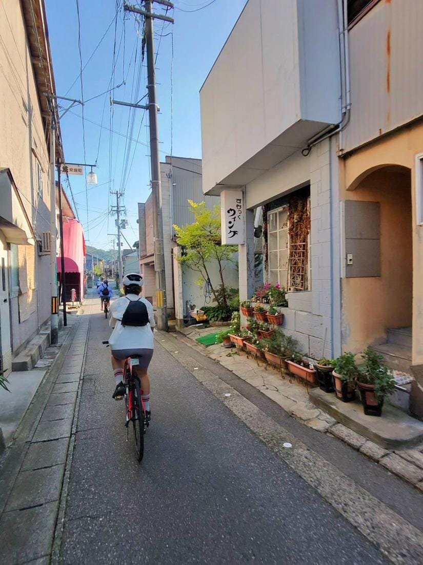 城下町巷弄(越後村上 町屋通り)裡的單車慢行,町屋與小店並排。